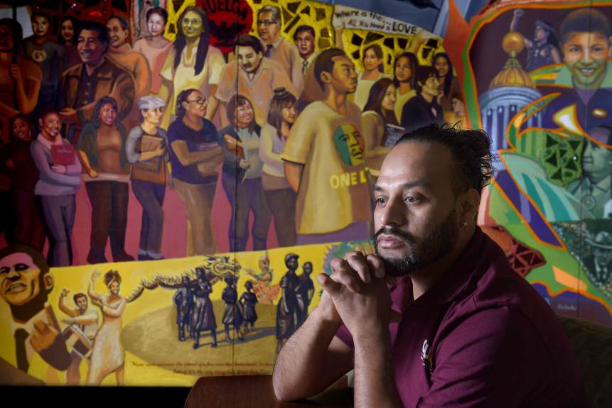 Cal State Dominguez Hills student Alejandro Campos Robledo has been having panic attacks since he learned he could lose his DACA status. Robledo often works through the stress with prayer and meditation. The mural behind him depicts the cultural diversity of the U.S. He fears he may get deported and have to leave his 11-year-old daughter behind. (Photo by Bill Alkofer, Contributing Photographer)